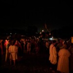 Guests at the first Pennsic Knowne World Courtesans Roman Bacchanal on August 7th, 2017 People in ancient Roman clothing standing and sitting while drinking, eating, and chatting outdoors at night