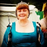 Courtesan Oriana of Xylina posing as she arrives at the Pennsic Knowne World Courtesans Social on August 10, 2017 A woman dressed in Renaissance clothing smiling