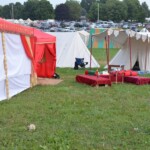 Setting up for the Pennsic Knowne World Courtesans Roman Bacchanal on August 6, 2018 A camp featuring medieval tents with an ancient Roman triclinium set up in the courtyard