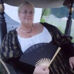 Courtesan Fortune St Keyne posing in Casa Bardicci's gondola at Pennsic in August of 2016 Closeup of a woman in Italian Renaissance clothing posing with a hand fan in a gondola