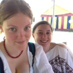 Courtesans Ginevra Fiammetta di Silvestri (right) and Eadyth Woderose (left) at the Pennsic Knowne World Courtesans Social on August 8th, 2016 Closeup of a woman in Italian Renaissance clothing and a woman in ancient Roman clothing outdoors with a colorful tent in the background