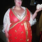 Courtesan Fortune St Keyne before the first Pennsic Knowne World Courtesans Roman Bacchanal on August 7th, 2017 A woman dressed in ancient Roman clothing smiling and holding a mug shaped like an upside down skull