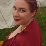 Courtesan Bianca Anguissola showing off her hairstyle before the first Pennsic Knowne World Courtesans Roman Bacchanal on August 7th, 2017<br><br>Hairstyle by Lucretia Marcella Closeup of a woman in ancient Roman clothing with an intricate updo hairstyle in front of some medieval style tents