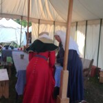 Courtesan Esa inghean Donnchaidh with her Laurel Beatriz Aluares de la Oya at their apprentice ceremony at Pennsic on August 3, 2017 Two people in medieval clothing bent over a table inside a medieval style tent
