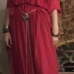 Courtesan Ginevra Fiammetta di Silvestri prepares to go to the first Pennsic Knowne World Courtesans Roman Bacchanal on August 7th, 2017 A woman in ancient Roman clothing and a red veil stands inside a yurt