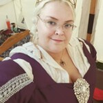 Courtesan Fortune St Keyne at Pennsic on August 3, 2018 Closeup of a woman in Italian Renaissance clothing next to a medieval style tent