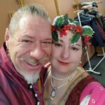Courtesans Honora de Cunningham and Bazyli Boleslaw z Krakowa at Twelfth Night in Northshield on January 14, 2023. Closeup of two people in Renaissance clothing smiling at the camera indoors