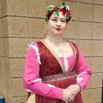 Courtesan Honora de Cunningham at Twelfth Night in Northshield on January 14, 2023. A woman in Italian Renaissance clothing wearing a gold stag pin standing indoors posing