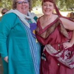 Courtesans Giovanna Ricci and Eleonora di Gerardo at Potrero War in Caid on May 26th, 2023.
<br><br>
Visit the Company of the Golden Fox (Calafia Courtesans Guild) Facebook group here: <a class='blue-link' href="https://www.facebook.com/groups/540612268076159">Facebook link</a> Two people in ancient and medieval clothing standing together and smiling at the camera outdoors